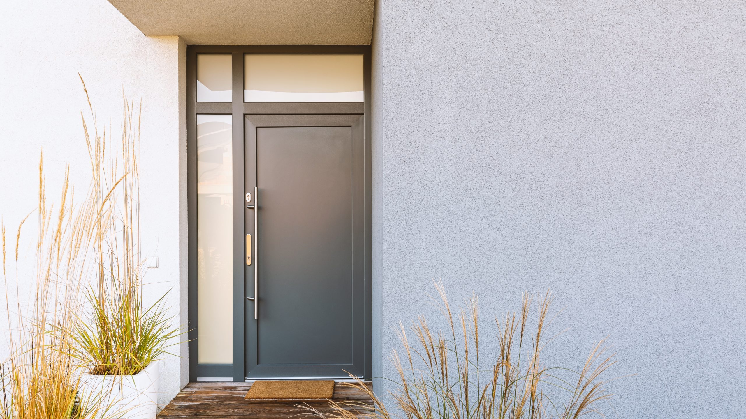 Grass in pot and wooden path in front of front door stylish suburban house