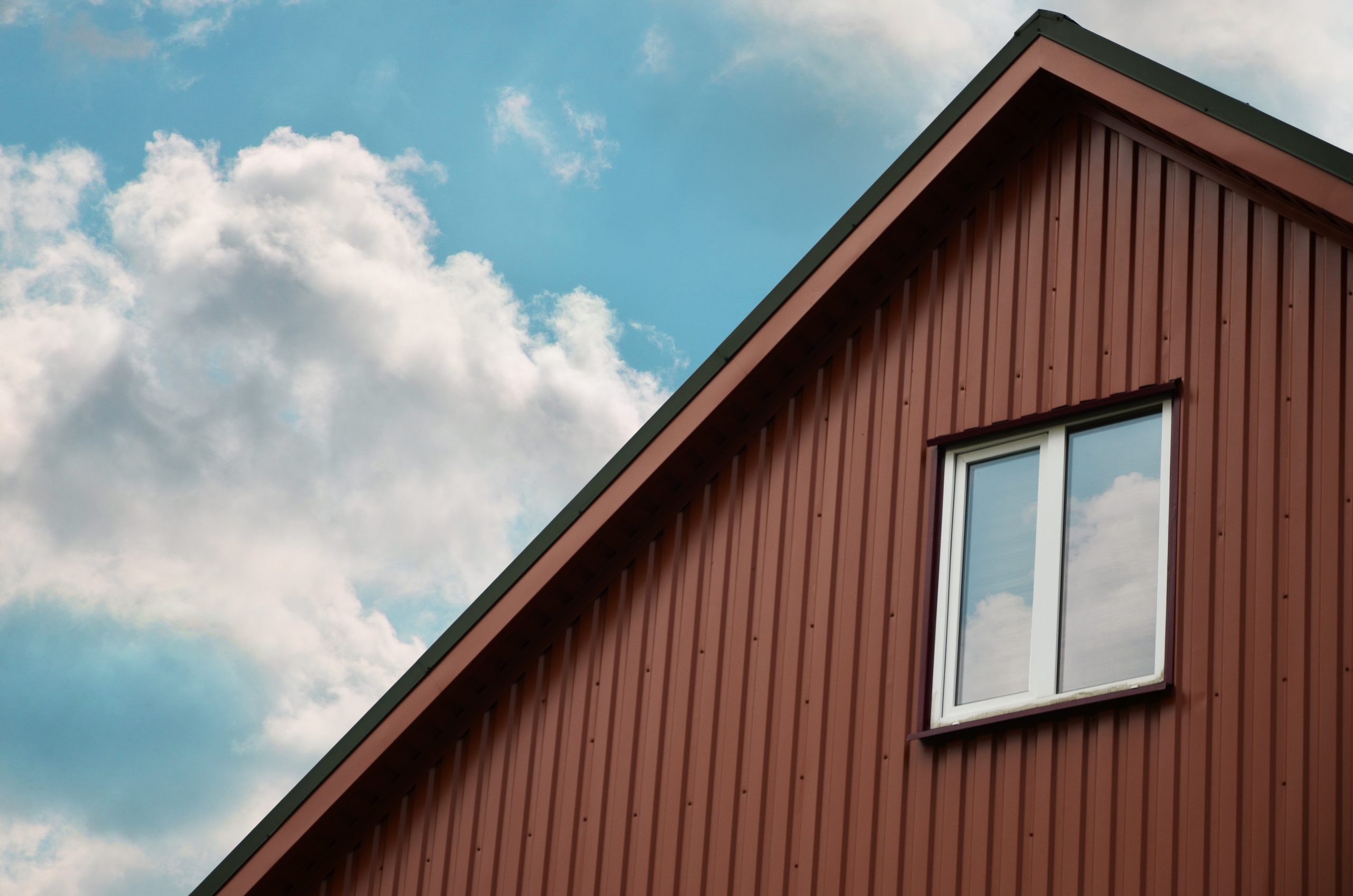 The brown attic with a small window on the sky background